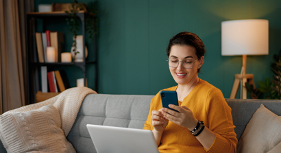 woman sat at home on her laptop and phone